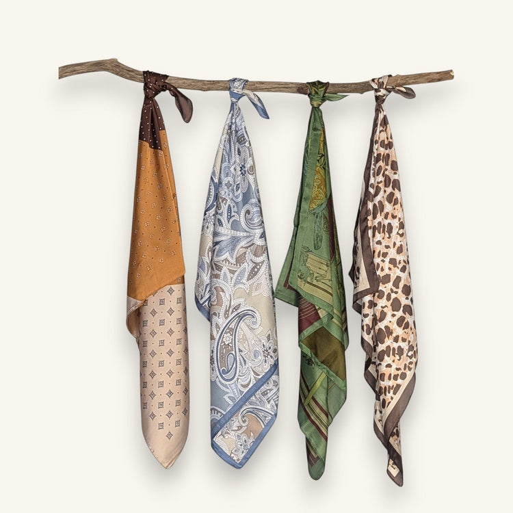 RecloStudio Halstücher in verschiedenen Mustern wie Leoparden-Print und Paisley, hängend an einem Ast präsentiert.