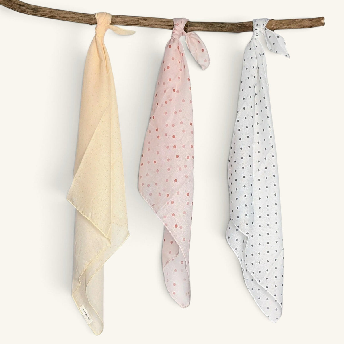 Drei RecloStudio Halstücher in Creme, Rosa und Hellblau mit Polka Dots, hängend an einem Ast